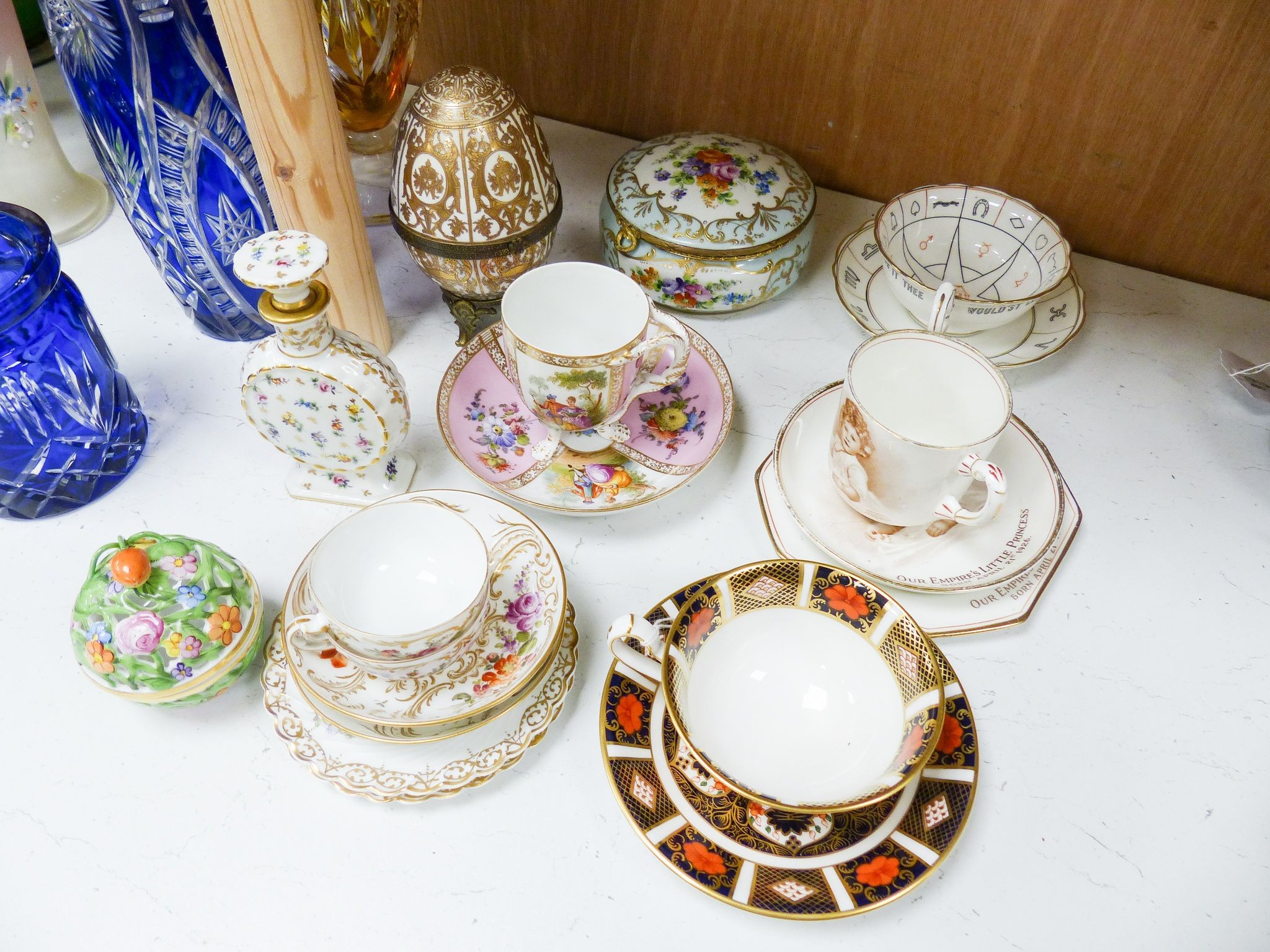 A group of Dresden and Continental porcelain cups and saucers boxes and covers and a scent bottle, 14 cm high